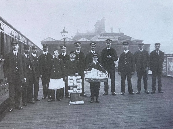 Staff posing to the platform of Midland station.  The boy in the centre holds a board full of postcards of Chesterfield for sale to passengers. - Alan Taylor